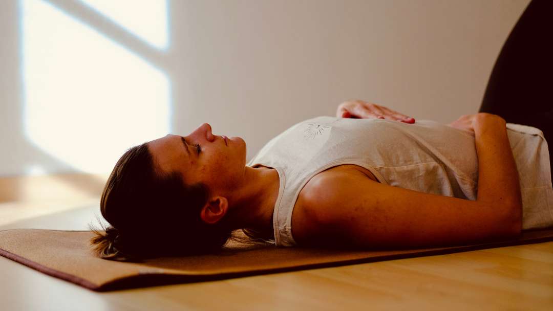 Rebecca Schröder im Yogaraum in Erding bei einer Meditation, autogenen Training oder progressiver Muskelentspannung im Liegen